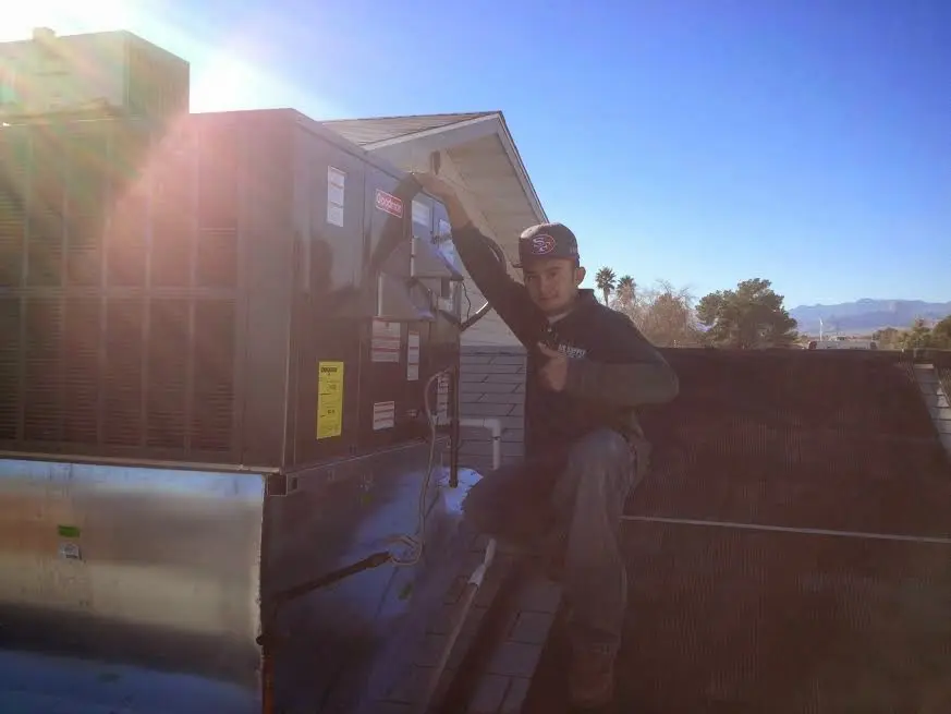 HVAC technician performing Air Duct Repair on a rooftop unit in Oneonta