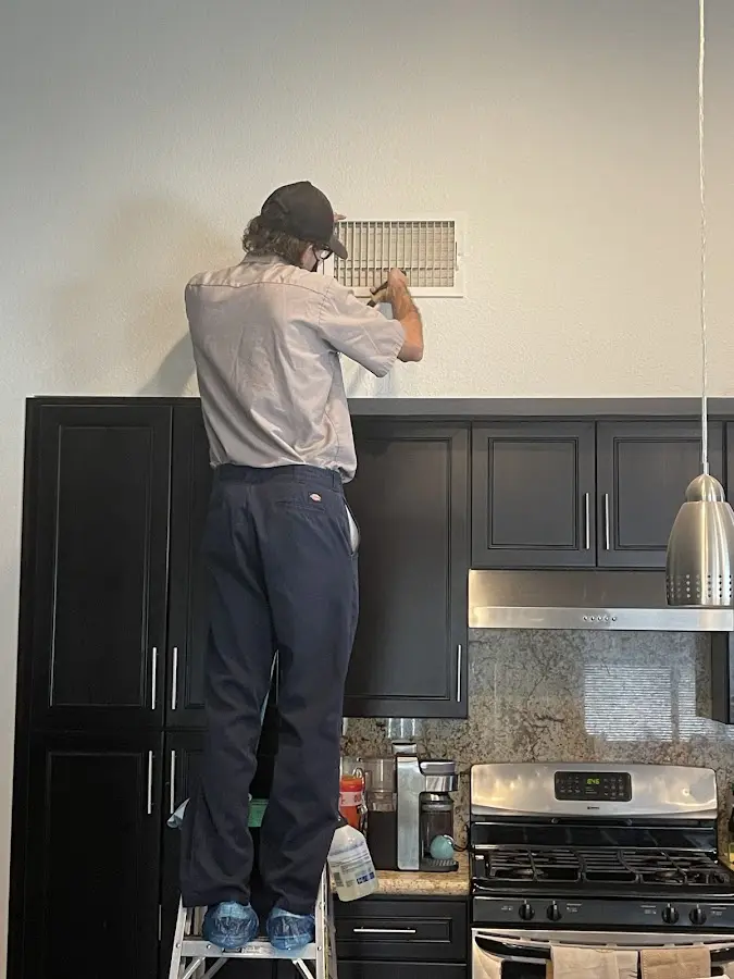 Technician inspecting an air vent during HVAC service in Oneonta